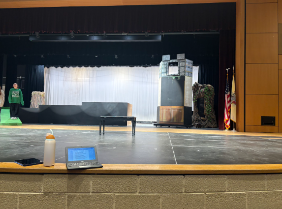 Behind the scenes of Into the Woods, with cast members practicing their lines and setting up the stage. 
